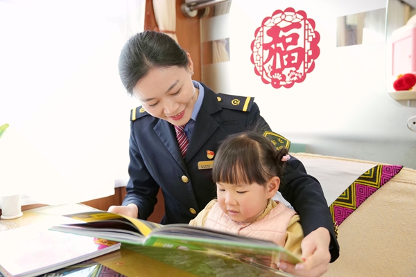 Z6次列车长莫梁娟带小旅客读儿童读物。曹烁摄