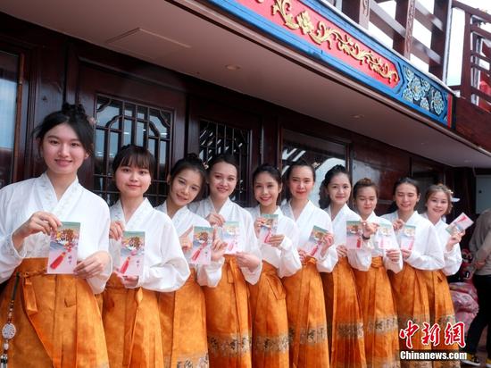 当地时间5月5日，正在马六甲交流的最大仿古福船“福宁”号受到马来西亚各界关注。图为马来西亚当地女生5日身着马面裙展示“福宁”号的相关文创产品。中新社记者 陈悦 摄